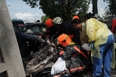 <p>SCDF rescuers cutting the metal to gain access to the rear passenger.  Medical Team from NUH (in blue) at scene</p>